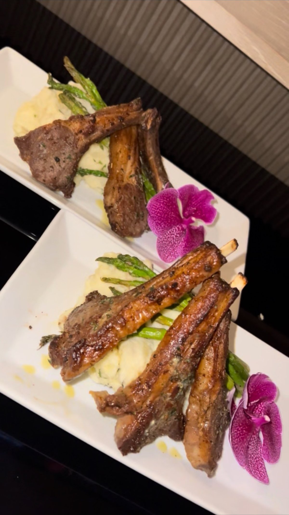 Grilled lamb chops with mashed potatoes, asparagus, and an orchid garnish