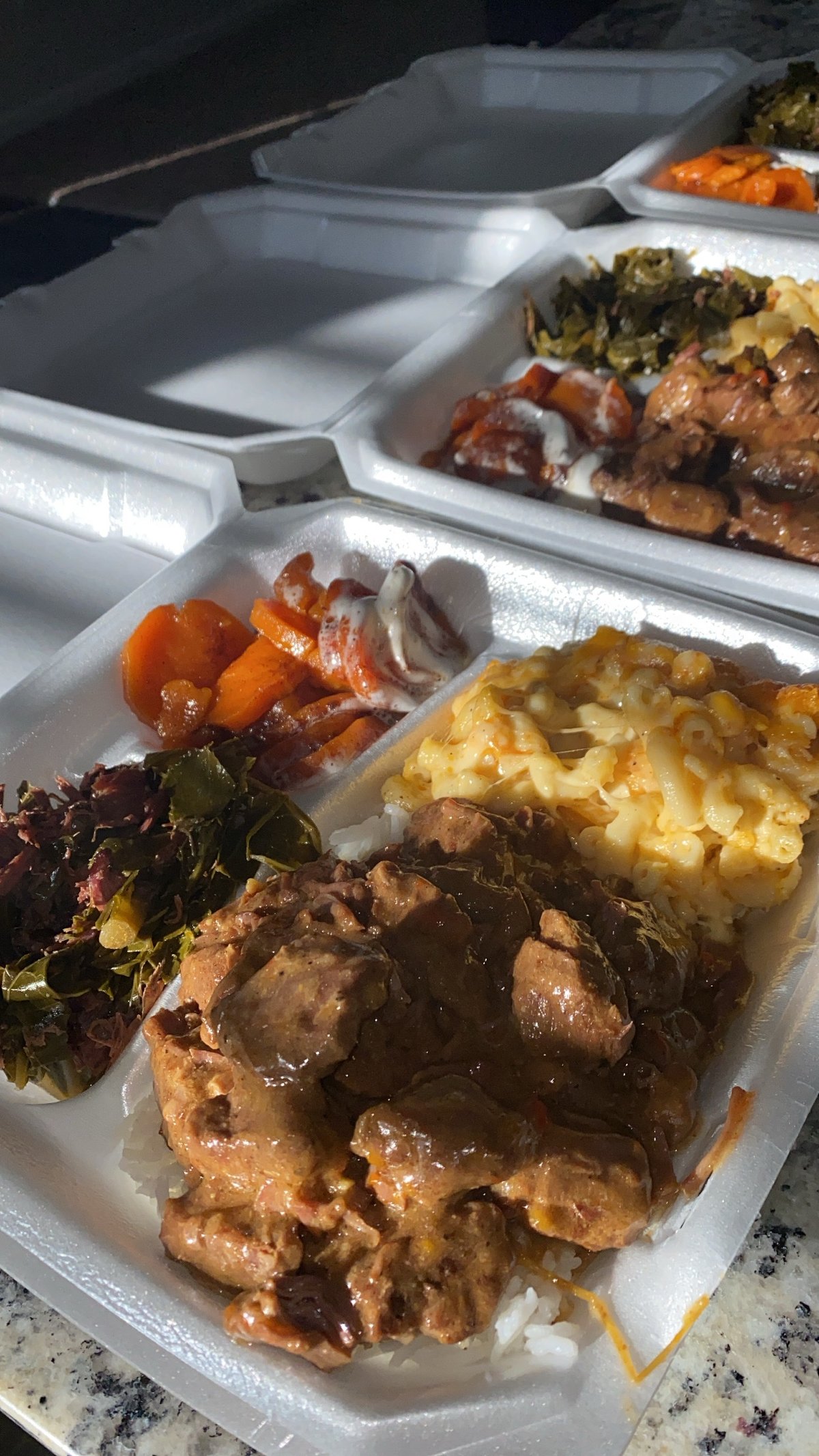 A to-go tray of braised beef, mac and cheese, collard greens, and candied carrots